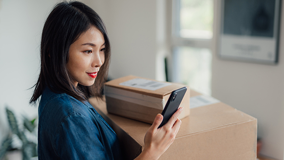 Woman holding phone by boxes