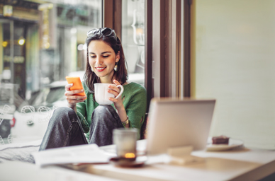 Woman with cup looking at mobile phone